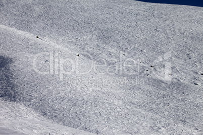 traces of skis and snowboards on off-piste slope at sun day
