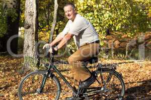 man rides his bike through the park in autumn