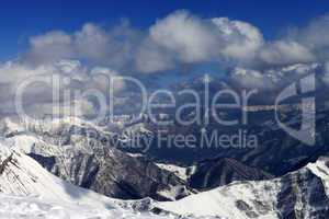 sunlit winter mountains in clouds, view from off-piste slope