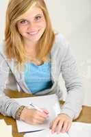 smiling student teenager sitting behind desk write