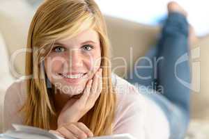 smiling student girl read book lying sofa