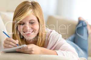 young teenage girl lying sofa writing notes