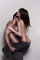 young topless couple embracing in jeans