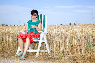 woman sitting in the garden chair in front of the wheat field