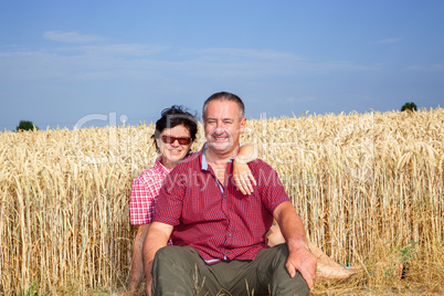 woman and man sitting on the wheat field