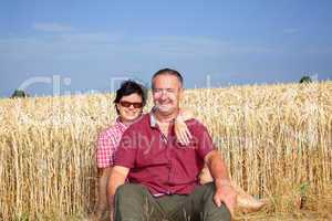 woman and man sitting on the wheat field