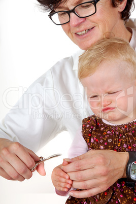 woman cuts toddler's fingernails