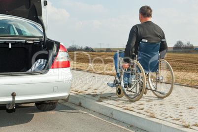 man in a wheelchair next to his car