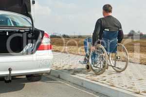 man in a wheelchair next to his car