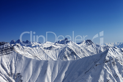 snowy winter rocks in sun day, view from ski slope