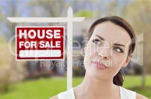 thinking woman in front of house and for sale sign