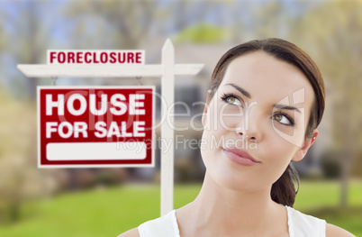 mixed race woman in front of house and foreclosure sign