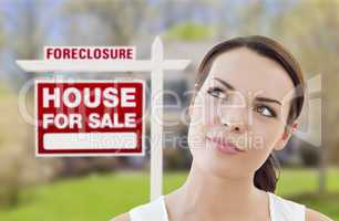 mixed race woman in front of house and foreclosure sign