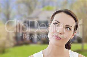 thoughtful mixed race woman in front of house