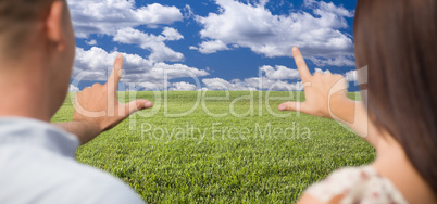 Couple Framing Hands Around Space in Grass Field