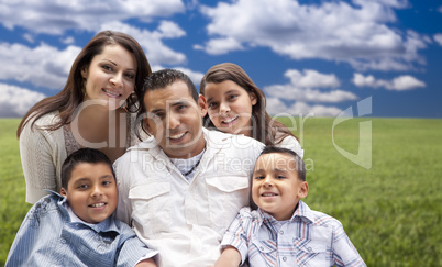 hispanic family portrait sitting in grass field