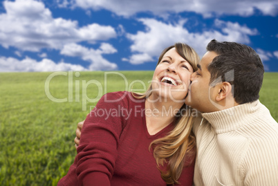 happy mixed couple sitting in grass field