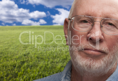 Melancholy Senior Man with Grass Field Behind