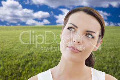 contemplative woman in grass field looking up and over