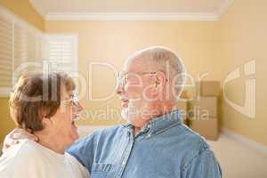 happy senior couple in room with moving boxes on floor