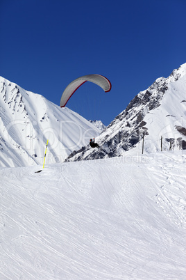 skydiver landing on ski slope at nice sun day