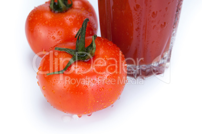 red tomatoes and glass of tomato juice on a white background