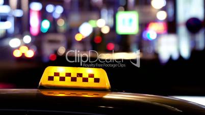 Timelapse of city traffic at night behind taxi sign