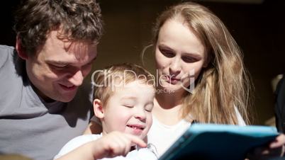 parents watching son playing game on touchpad