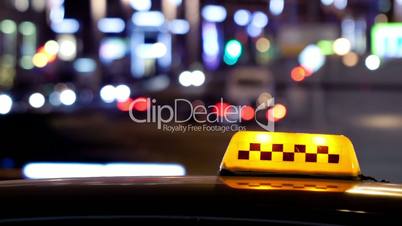 timelapse of city traffic at night behind taxi sign