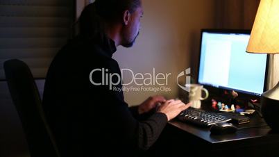 man working computer at home office night time