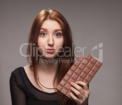 portrait of  puzzled young girl with the big chocolate