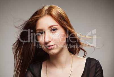 portrait of beautiful girl with fluttering hairon a grey