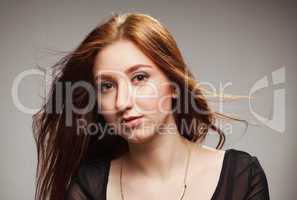 portrait of beautiful girl with fluttering hairon a grey