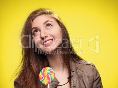happy young girl with lollipop on a yellow