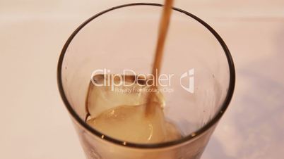 pouring cola in a glass with ice