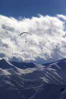 winter mountain with clouds and silhouette of parachutist