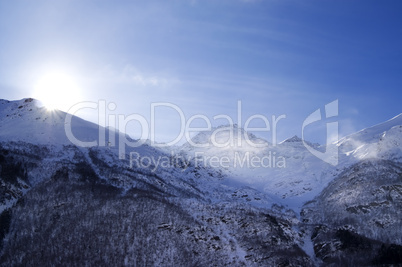 snowy mountains in haze and sky with sun, view from off piste sl