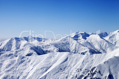 snowy winter mountains and blue sky, view from ski slope