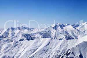 snowy winter mountains and blue sky, view from ski slope