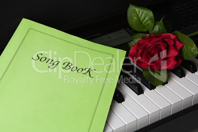 piano keys, song book,and rose flower