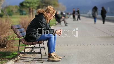 sad blonde women sitting a bank
