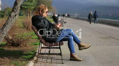 attractive blonde sitting bank and using tablet computer