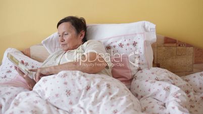 Senior woman with digital tablet in bed