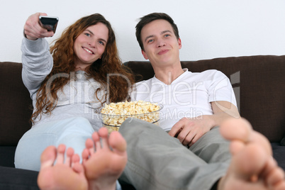Junges Pärchen schauen tv und essen Popcorn