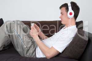 Junger Mann hört Musik auf dem Sofa