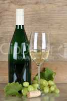 Weißwein in Flasche und Weinglas vor Holzhintergrund