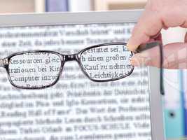 hand holds glasses in front of the computer screen