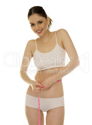 beautiful young woman measuring her waistline