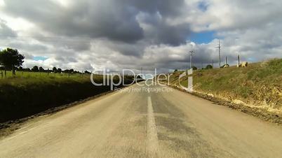 Driving car on the road in green fields