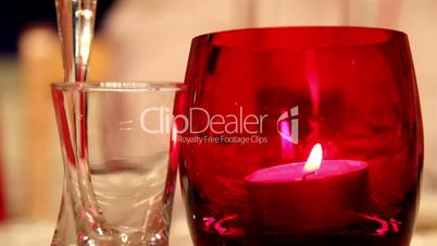 A candlelight inside a red glass and a small glass